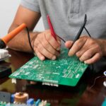 Tech Savvy ATL technician performing micro soldering on a smartphone motherboard